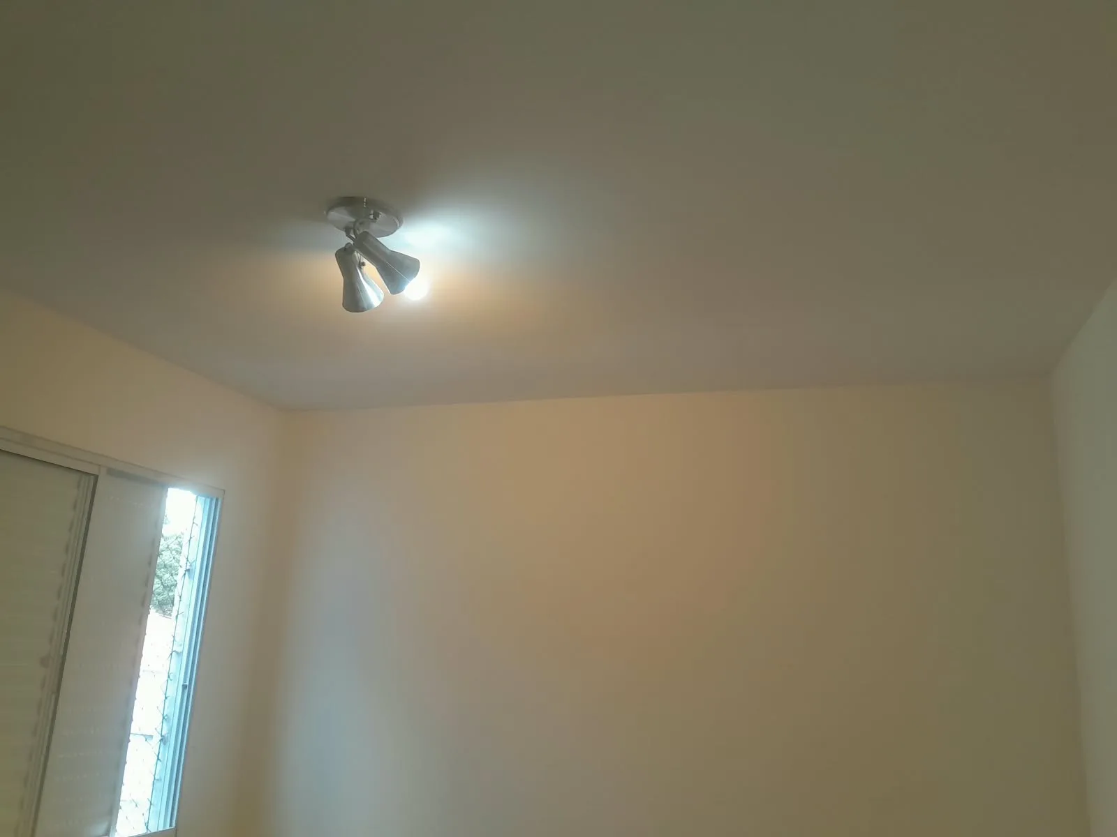 Quarto de paredes e teto lisos, com janela e luminária