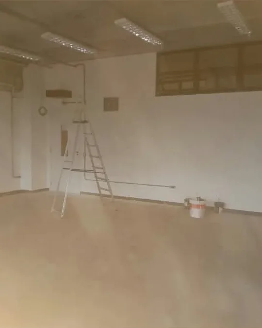 Sala de parede branca pronta, com escada e balde de tinta