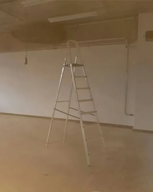 Sala ampla de parede branca, com uma escada no meio